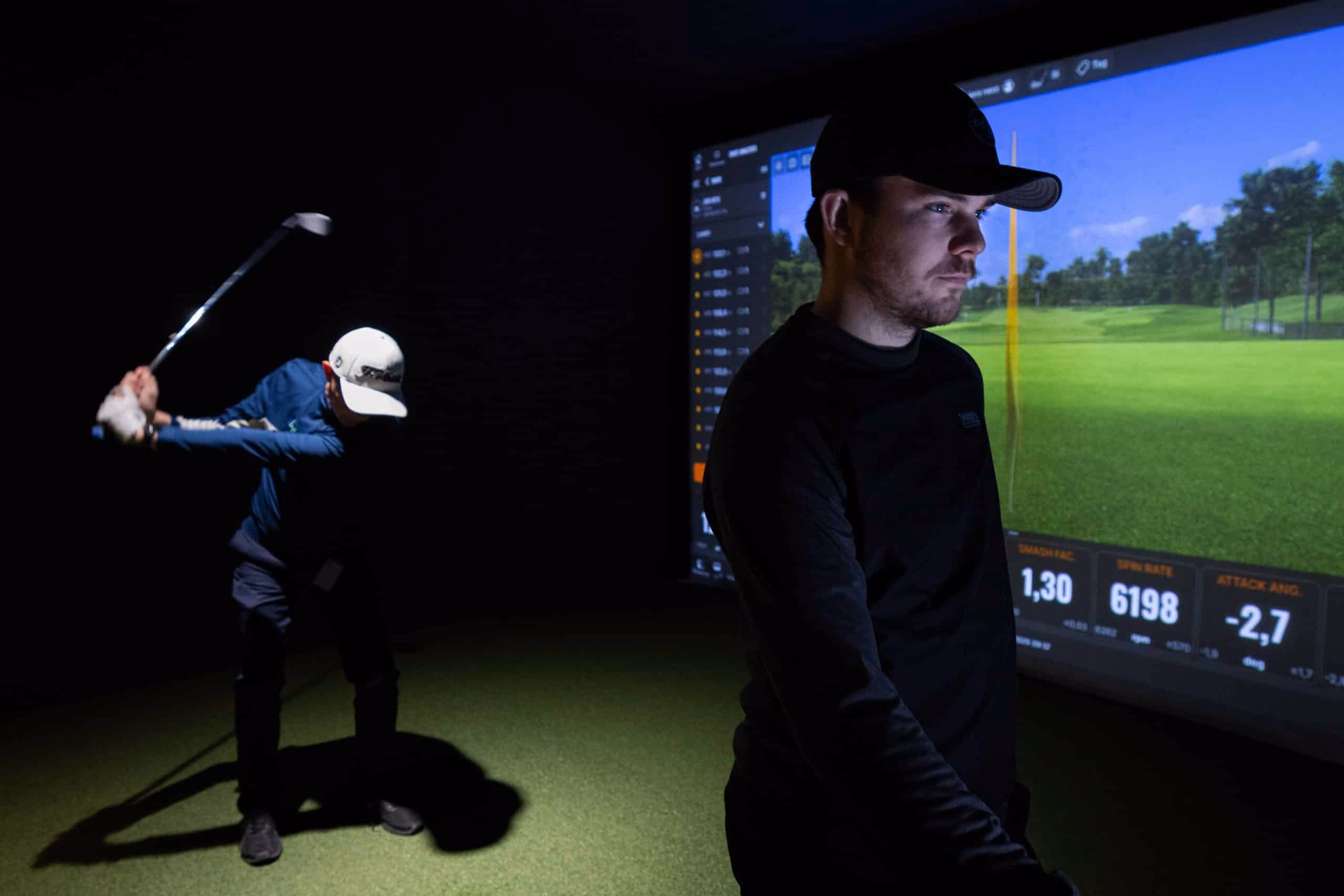 Golfers practising in a TrackMan simulator
