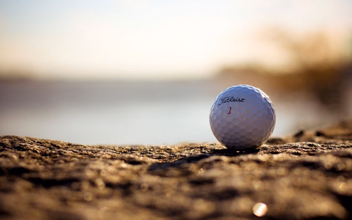 Titleist golf ball resting on rough ground